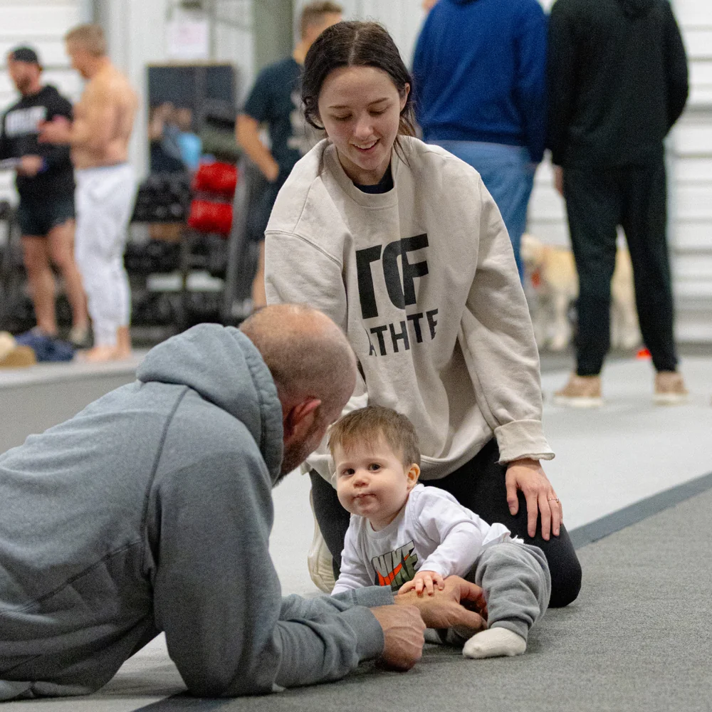 A family together on the gym floor at True Grit Fitness, showing the welcoming community in Edmond, Oklahoma