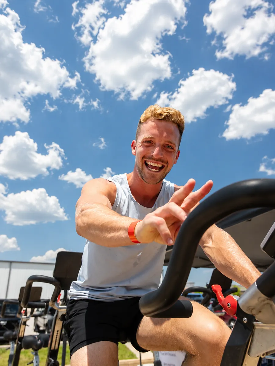 Member smiling on an assault bike during an outdoor workout at True Grit Fitness