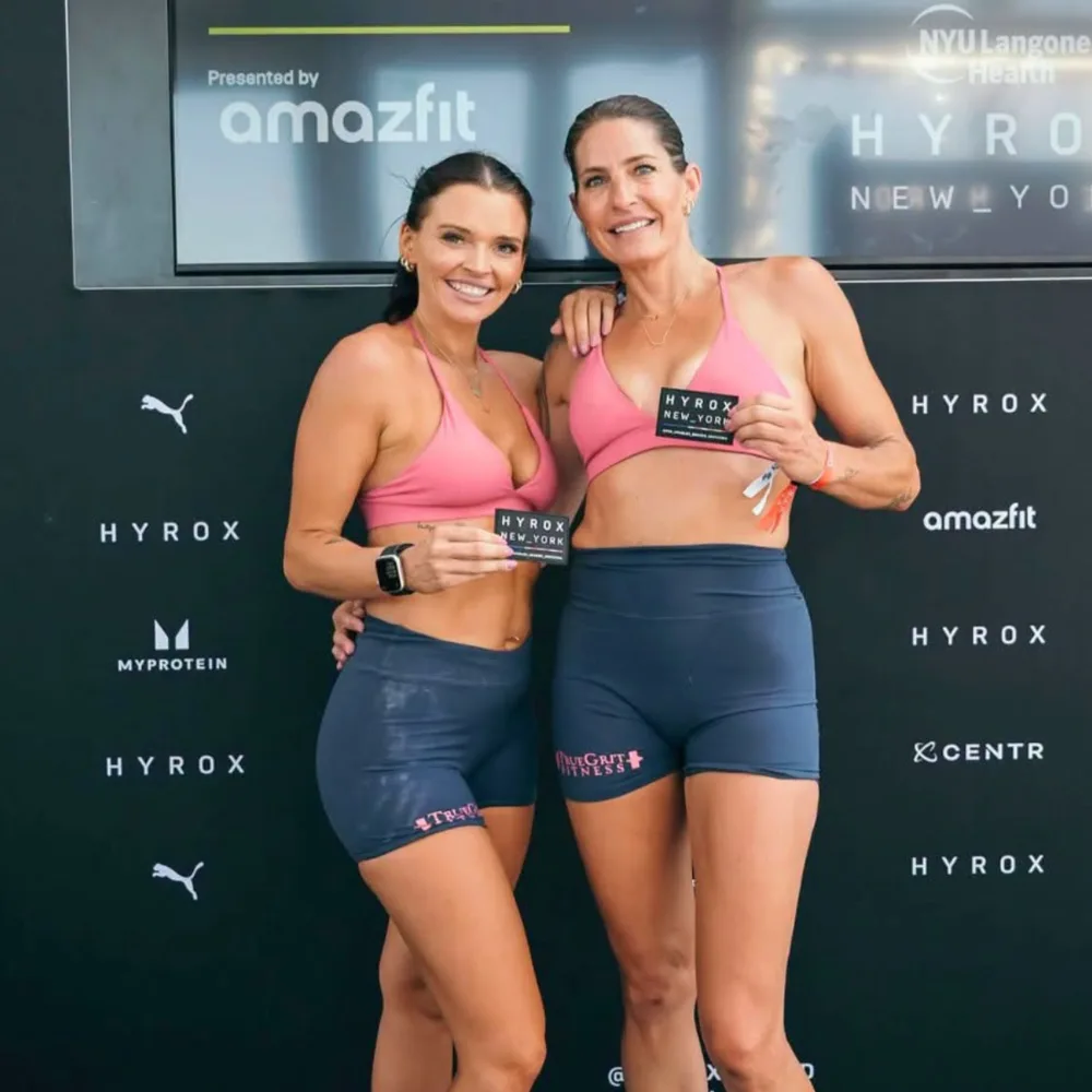 True Grit Fitness members holding their Hyrox New York race cards at the finish