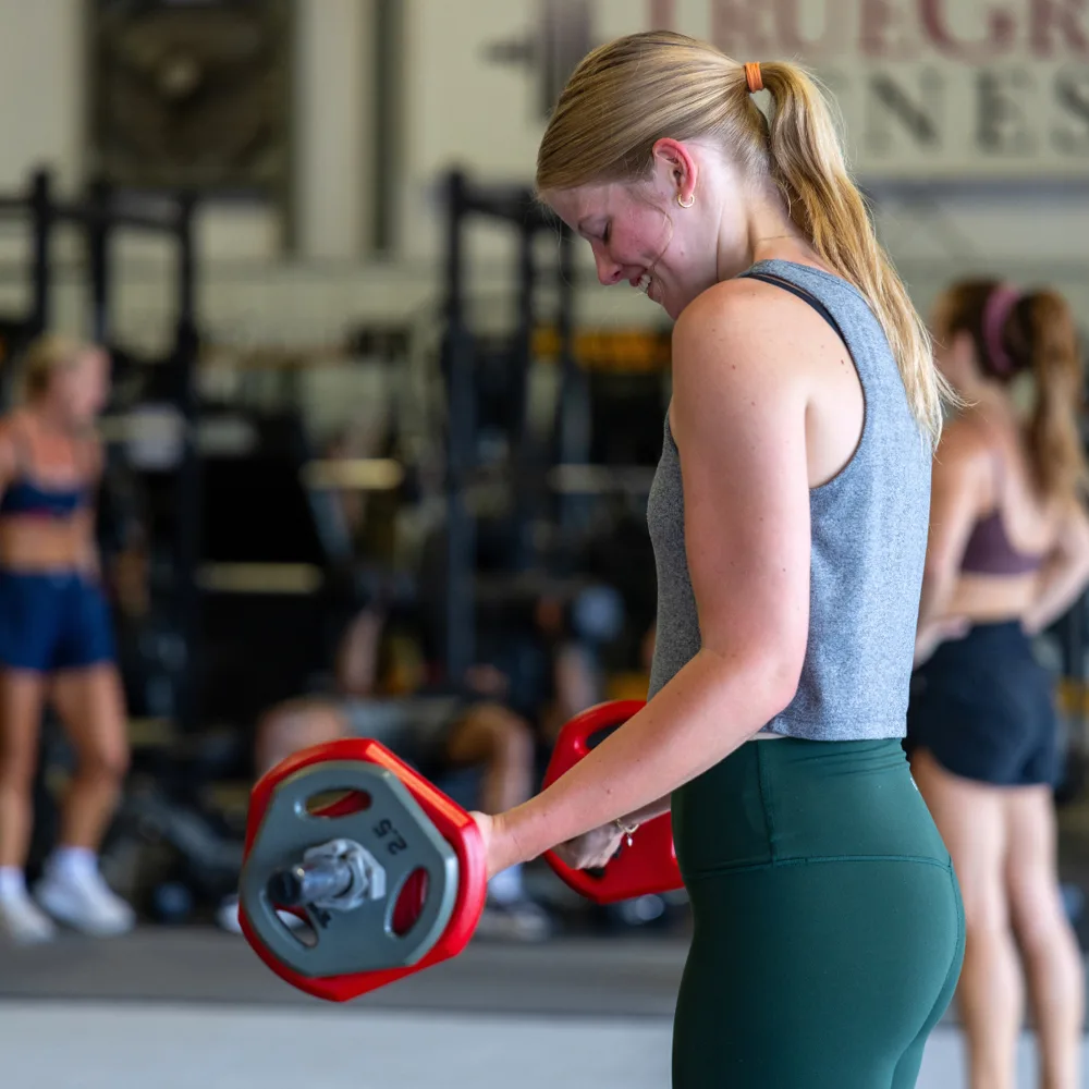 Client training with weight plates during a one-on-one personal training session at True Grit Fitness