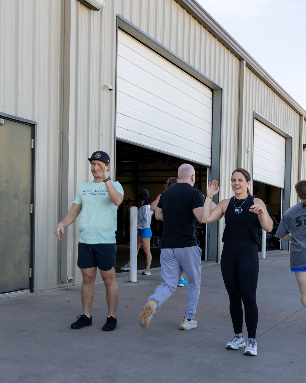 Corbi Hodge high-fiving members finishing a workout outside True Grit Fitness in Edmond, Oklahoma