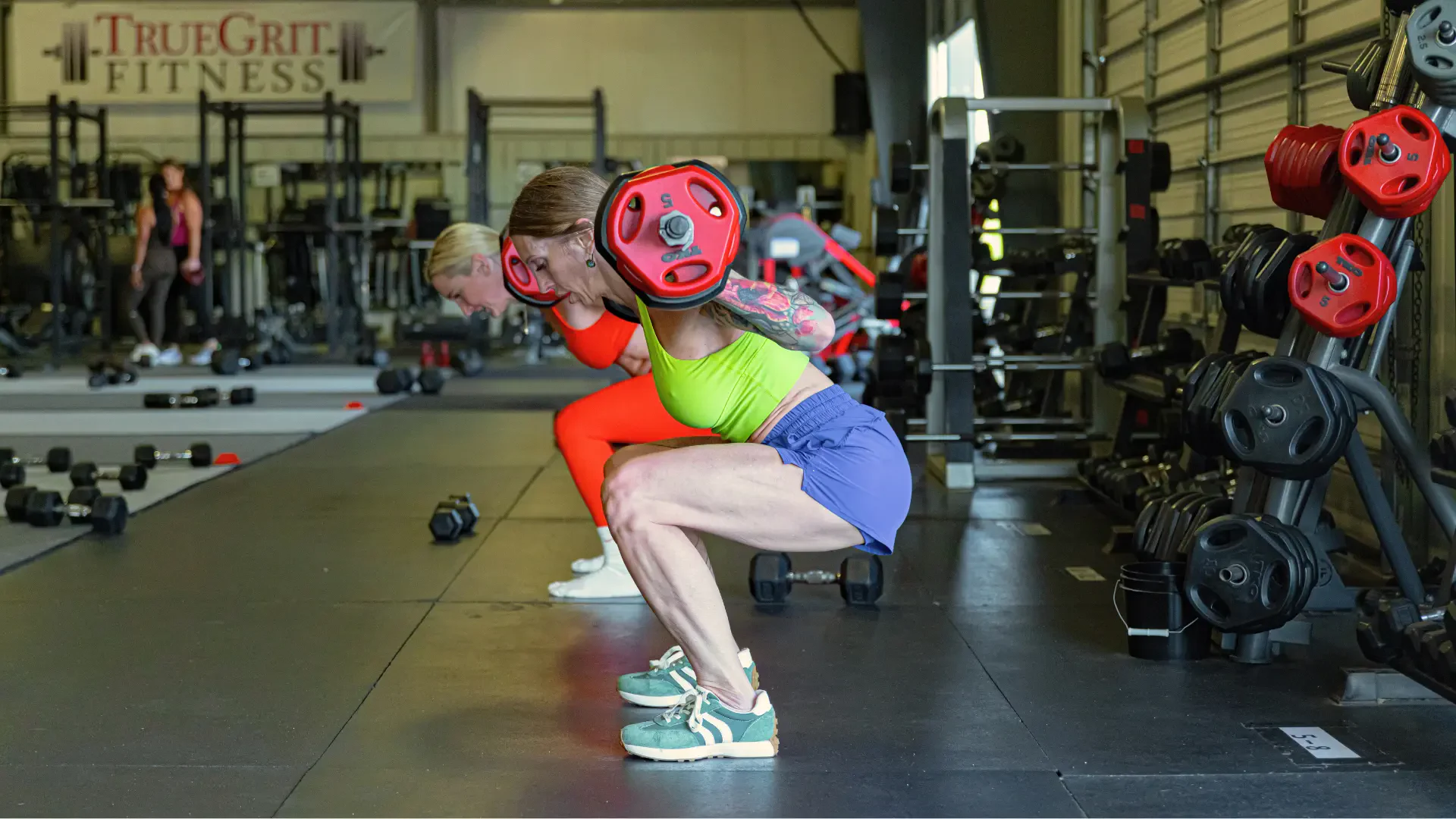 Coach loading a barbell with a member at True Grit Fitness in Edmond, Oklahoma