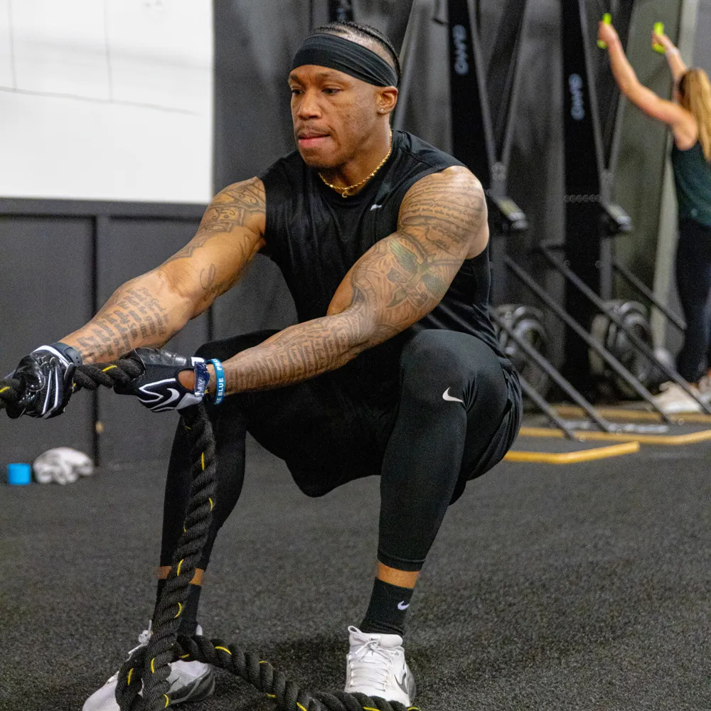 Member pulling battle ropes in a squat during strength training at True Grit Fitness