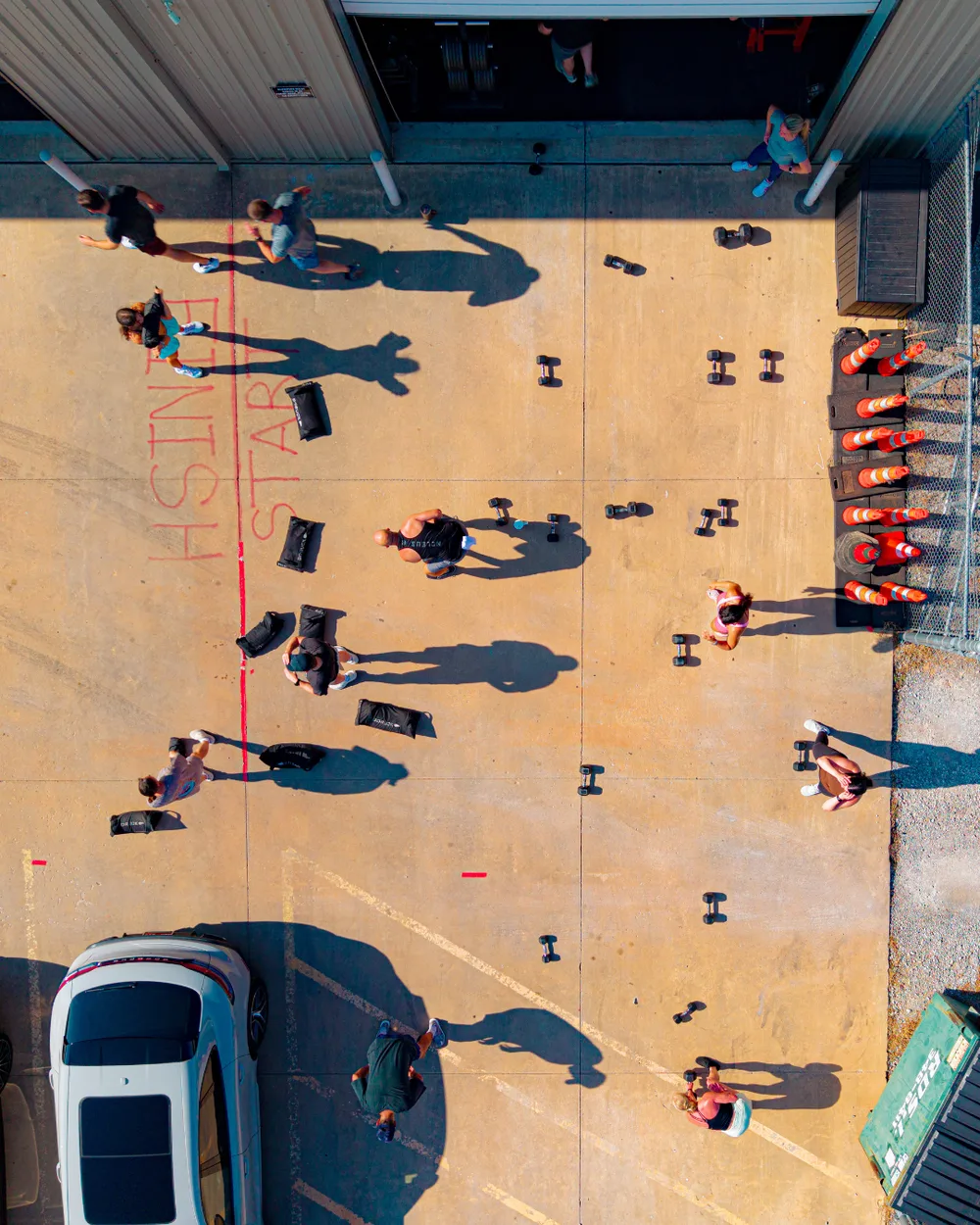 Aerial view of a True Grit Fitness outdoor group workout with dumbbells and sandbags in Edmond, Oklahoma